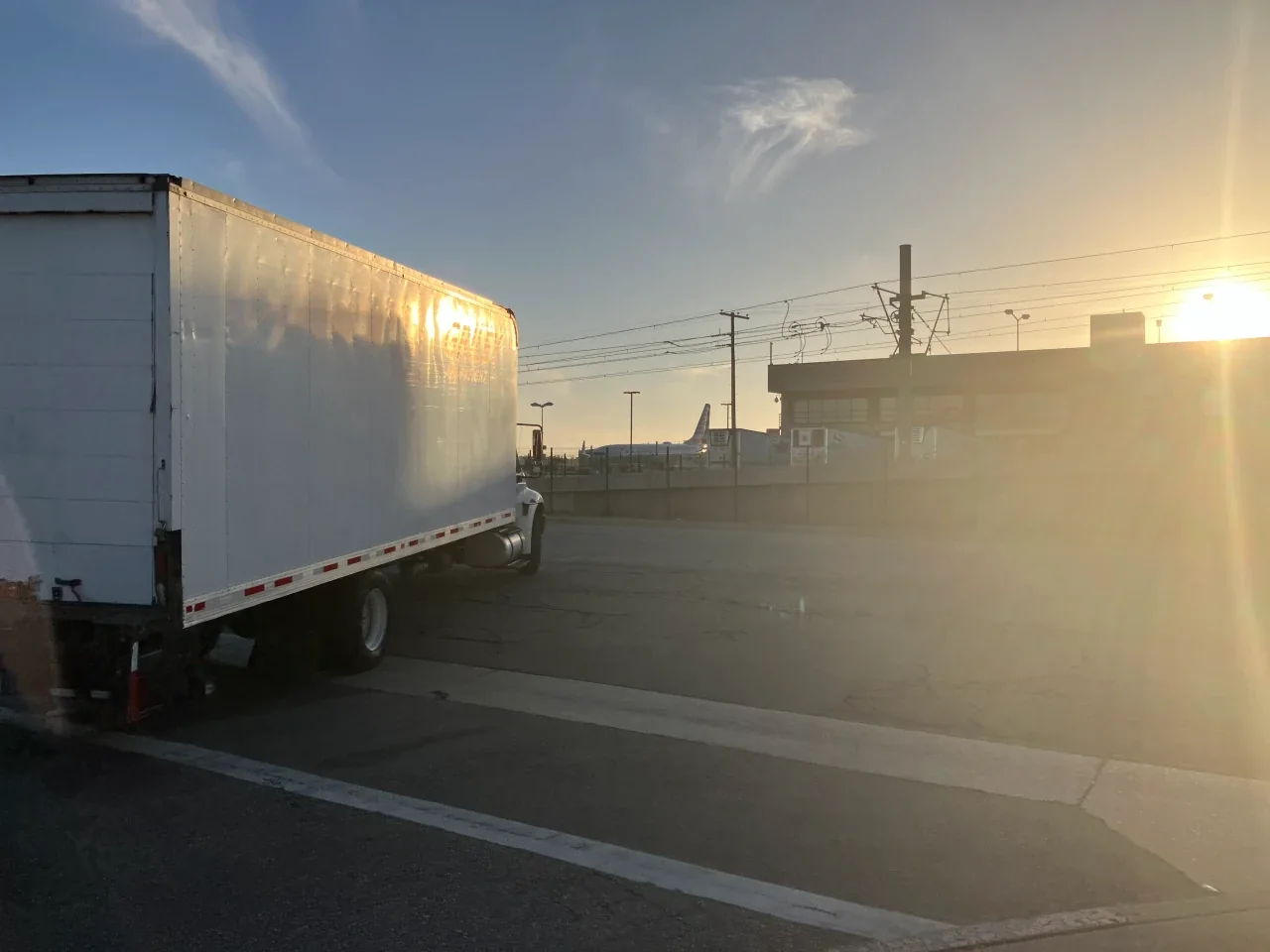 Walking past the airport perimeter fence toward the air cargo district at sunset