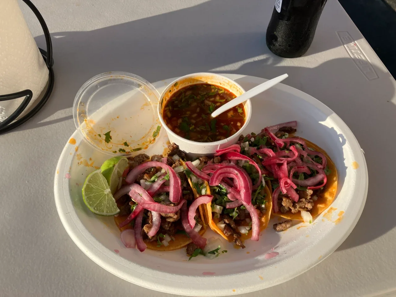 Close-up of the Nikos Red Tacos plate with pickled red onions and consommé